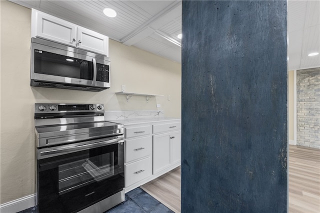 kitchen with white cabinets, light wood-type flooring, and appliances with stainless steel finishes