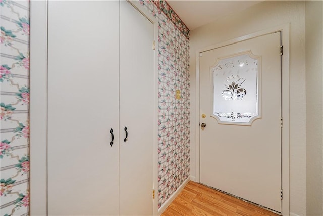 entrance foyer with wallpapered walls, light wood finished floors, and baseboards