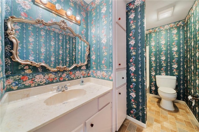 bathroom featuring baseboards, vanity, and toilet