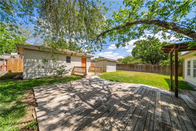 wooden deck featuring a fenced backyard, an outbuilding, and a yard