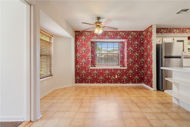 empty room with baseboards, visible vents, wallpapered walls, ceiling fan, and light floors