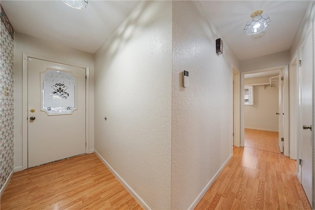 hallway with light wood-style flooring and baseboards