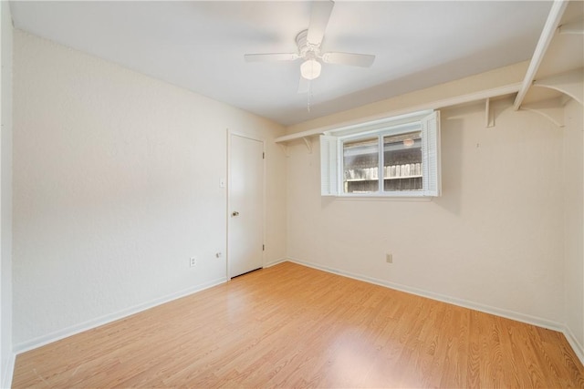 empty room with light wood finished floors, a ceiling fan, and baseboards