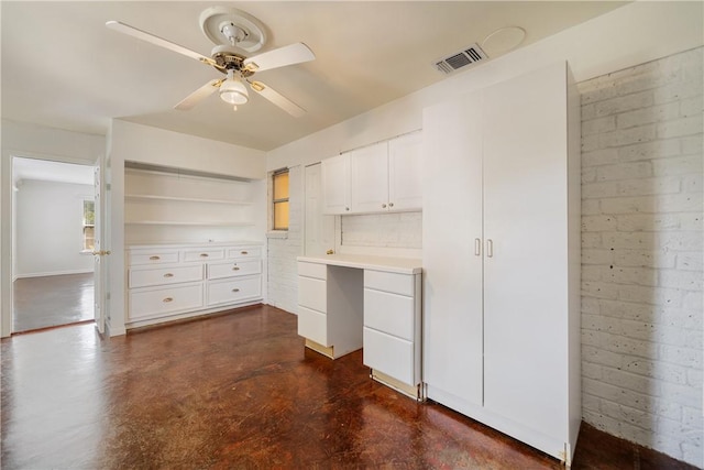 interior space with built in study area, visible vents, a ceiling fan, and finished concrete floors