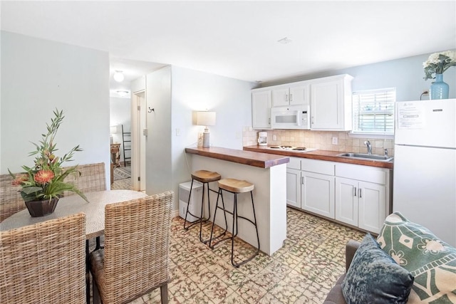 134 N Alister St Unit 23, Port Aransas, TX 78373 - kitchen with white cabinets, a sink, white appliances, a kitchen breakfast bar, and tasteful backsplash