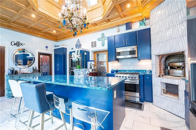 121 Glenmore St, Corpus Christi, TX 78412 - kitchen featuring appliances with stainless steel finishes, blue cabinets, a chandelier, light marble finish flooring, and a kitchen bar