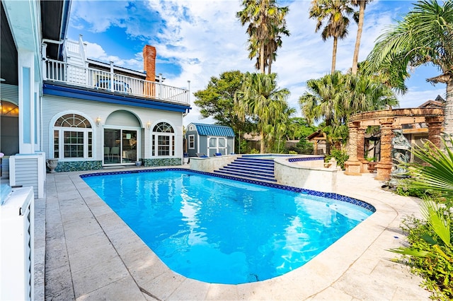 view of pool featuring a patio and a shed