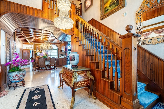 staircase featuring wood walls and a notable chandelier