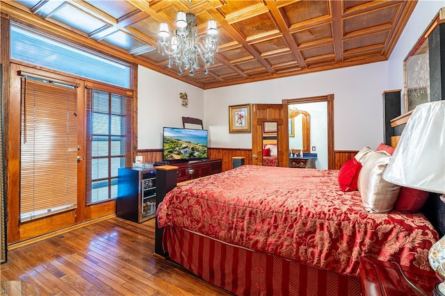 bedroom with wood walls, a notable chandelier, coffered ceiling, dark hardwood / wood-style floors, and crown molding