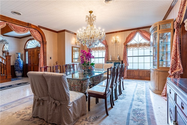 dining area featuring ornamental molding, wooden walls, a textured ceiling, and a chandelier