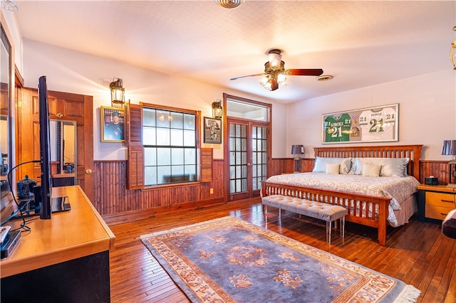 bedroom with dark hardwood / wood-style flooring, wooden walls, and ceiling fan