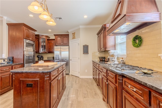 kitchen featuring stainless steel appliances, custom range hood, crown molding, a center island, and pendant lighting