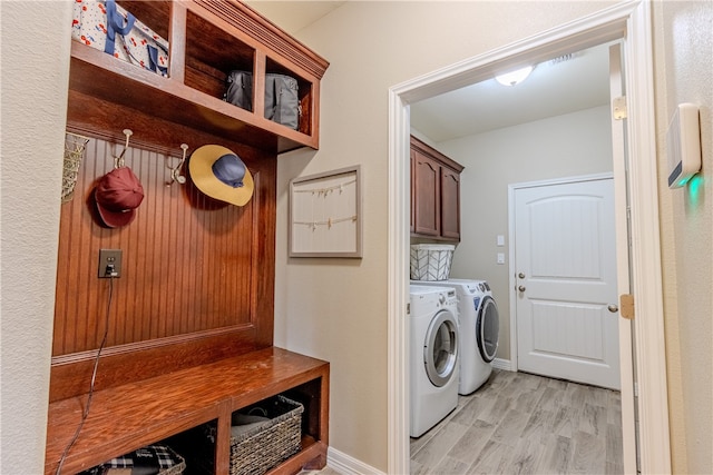 laundry room featuring cabinets, washer and dryer, and light hardwood / wood-style floors