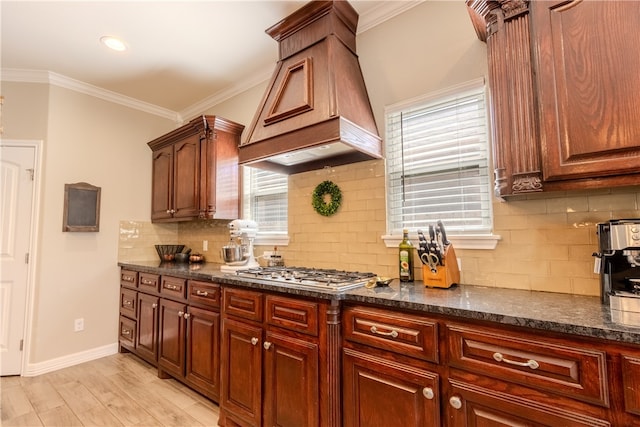 kitchen with a wealth of natural light, crown molding, custom exhaust hood, and light hardwood / wood-style floors