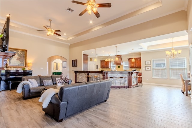 living room featuring light wood-type flooring, a tray ceiling, and ornamental molding