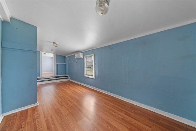 spare room with hardwood / wood-style flooring, lofted ceiling, and an AC wall unit