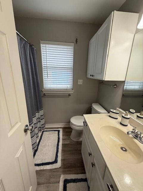 full bath with baseboards, toilet, a shower with curtain, wood finished floors, and vanity