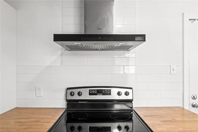 kitchen with backsplash, electric range, extractor fan, and butcher block counters