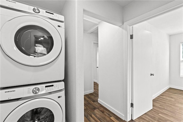 washroom with baseboards, laundry area, stacked washer / dryer, and wood finished floors