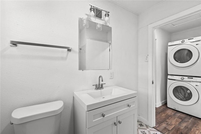 bathroom with vanity, stacked washer and clothes dryer, and toilet