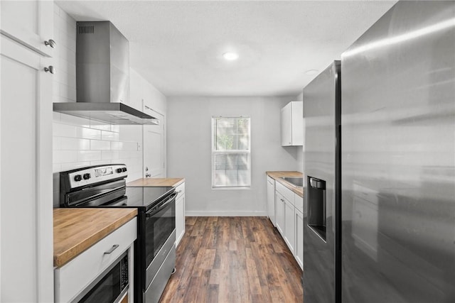 kitchen with wall chimney range hood, dark wood-style flooring, appliances with stainless steel finishes, tasteful backsplash, and white cabinetry