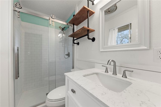 bathroom with vanity, toilet, a shower with shower door, and a textured ceiling