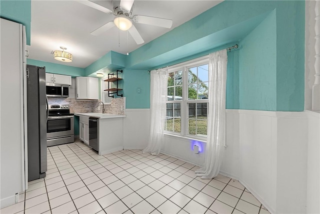 kitchen featuring decorative backsplash, stainless steel appliances, ceiling fan, light tile patterned floors, and white cabinetry