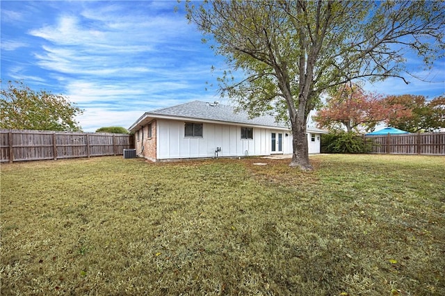 rear view of property with central AC and a lawn