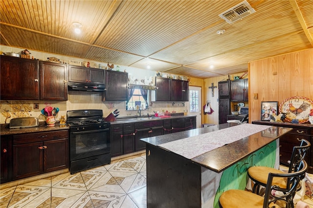 kitchen with sink, tasteful backsplash, a kitchen bar, a center island, and black range with gas stovetop