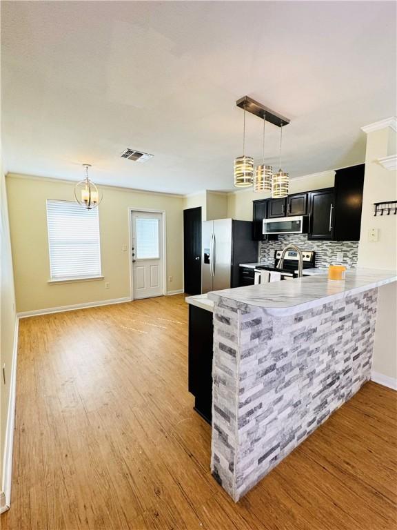 2113 Encino Dr, Corpus Christi, TX 78414 - kitchen with dark cabinetry, stainless steel appliances, a peninsula, baseboards, and backsplash