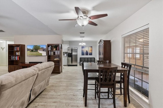 dining space featuring visible vents, light wood-style flooring, and ceiling fan with notable chandelier