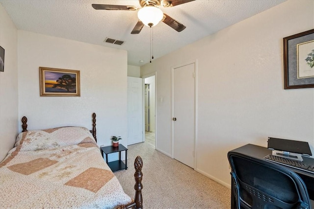 bedroom featuring light carpet, visible vents, a textured ceiling, and ceiling fan