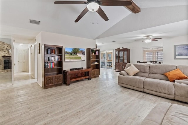 living room with visible vents, a large fireplace, light wood-style floors, and vaulted ceiling with beams