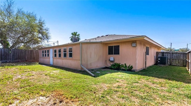 back of house featuring a yard, a fenced backyard, and central AC