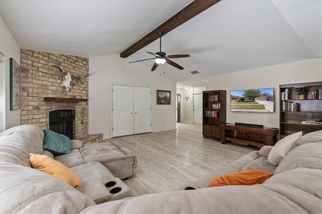 living area featuring lofted ceiling with beams, wood finished floors, a fireplace, and ceiling fan