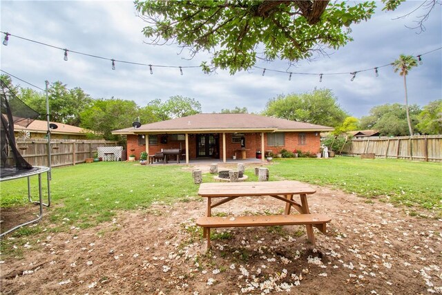 1512 Palo Blanco, Beeville, TX 78102 - rear view of house with a lawn, a fenced backyard, a patio area, and a trampoline