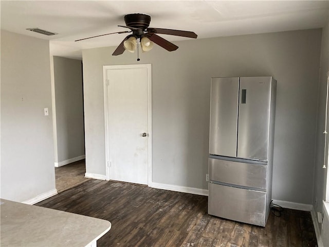 unfurnished bedroom featuring visible vents, a ceiling fan, freestanding refrigerator, baseboards, and dark wood-style flooring