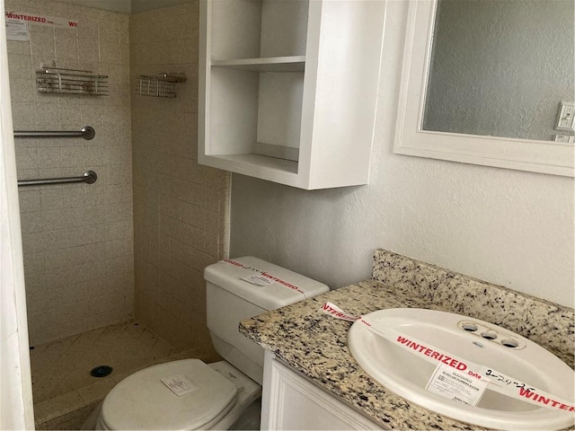 full bathroom with toilet, a stall shower, vanity, and a textured wall