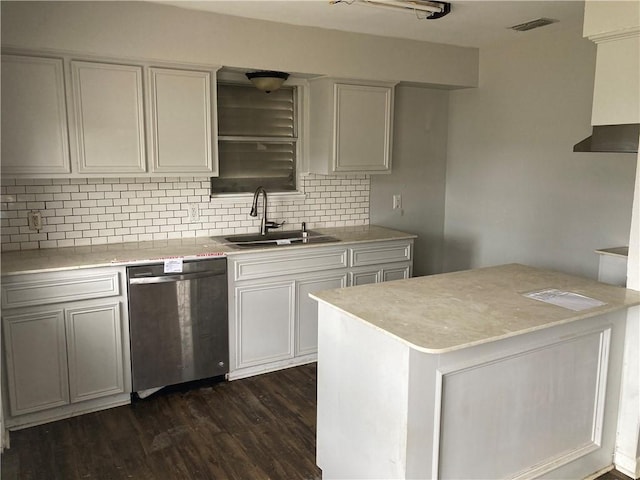 kitchen with dark wood-style floors, a sink, decorative backsplash, light countertops, and stainless steel dishwasher