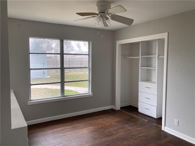 unfurnished bedroom with baseboards, multiple windows, a closet, and dark wood finished floors