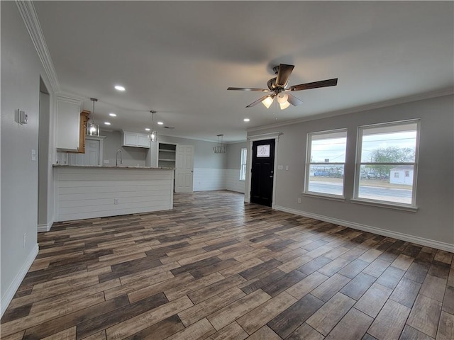 unfurnished living room featuring ceiling fan, dark hardwood / wood-style flooring, sink, and ornamental molding