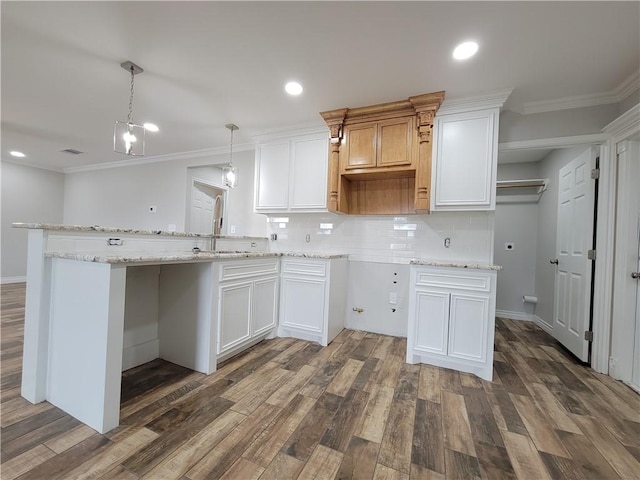 kitchen featuring white cabinets, sink, hanging light fixtures, crown molding, and decorative backsplash