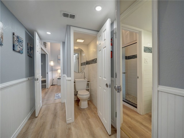 bathroom featuring wood-type flooring, toilet, and a tile shower