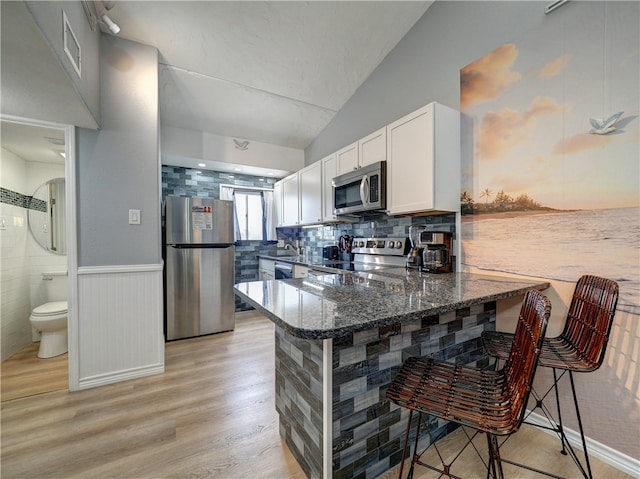 kitchen featuring white cabinetry, kitchen peninsula, appliances with stainless steel finishes, and a breakfast bar area