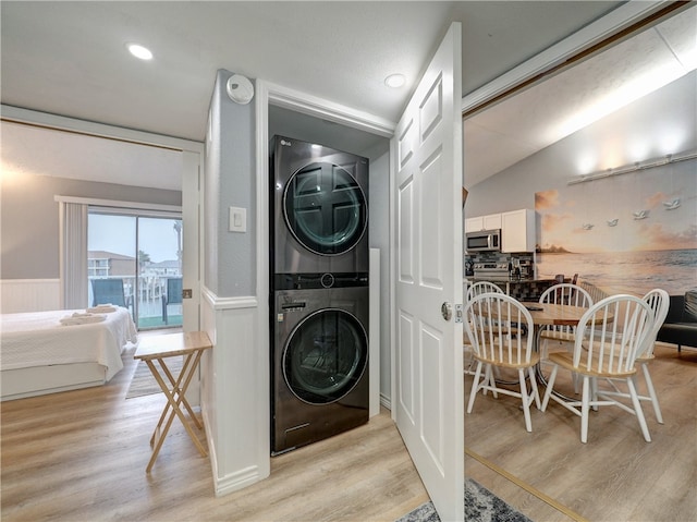 laundry area with light hardwood / wood-style floors and stacked washer and dryer