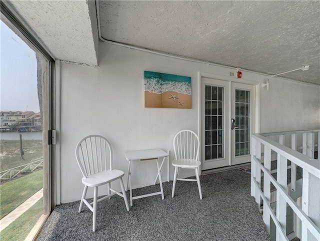 sunroom featuring french doors and a water view