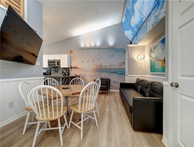 dining space with light hardwood / wood-style floors and vaulted ceiling