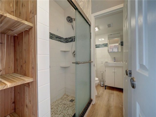 bathroom featuring an enclosed shower, wood-type flooring, toilet, and vanity