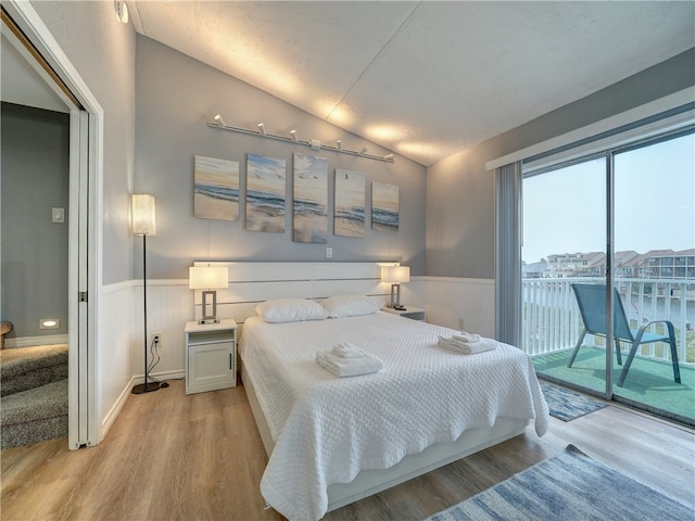 bedroom with access to exterior, light hardwood / wood-style floors, and lofted ceiling