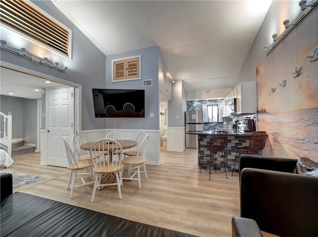 dining space featuring light wood-type flooring and high vaulted ceiling